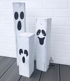 two wooden blocks decorated with black and white painted faces, one has a ghost's face on it