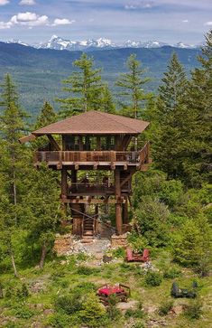 a tall wooden tower sitting in the middle of a forest next to a lush green hillside