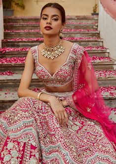 a woman sitting on some steps wearing a pink and white dress