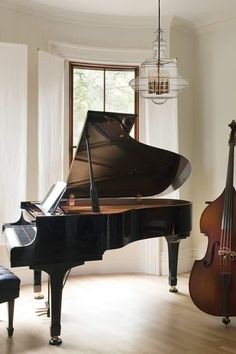 a grand piano sitting next to a black piano in a living room with a chandelier