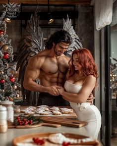 a man standing next to a woman in front of a table with cookies on it