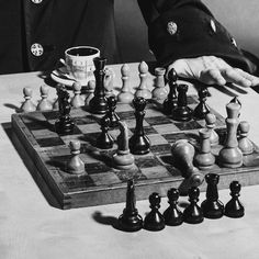 a man is playing chess on a table with his hands in the air and one hand reaching for the pieces