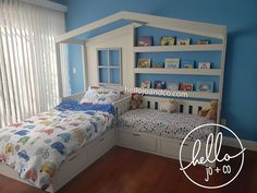 a child's bedroom with blue walls and white bedding, built in bookshelves