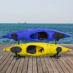 two kayaks sitting on top of a wooden dock next to the ocean