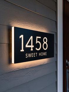 a house number sign mounted to the side of a building with lights on it's sides