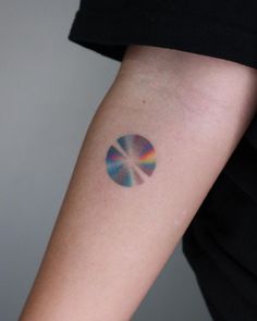 a woman's arm with a colorful disc tattoo on the left side of her arm