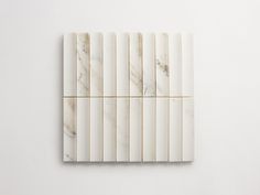 four pieces of white marble sitting on top of each other in front of a white wall