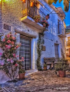 an old building with potted plants and flowers on the balconies