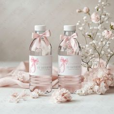 two water bottles with pink bows and ribbons on them next to some baby's breath flowers