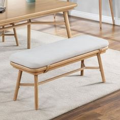 a wooden bench sitting on top of a carpeted floor next to a table and chairs