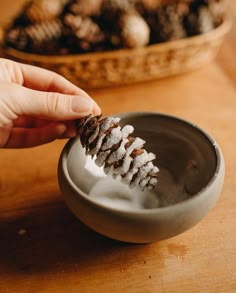 a person is scooping some food out of a small bowl on a wooden table