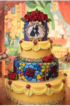 a three tiered cake decorated with stained glass and red roses, on a table