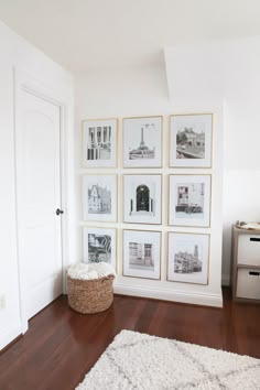 a white room with pictures on the wall and a basket in front of it,