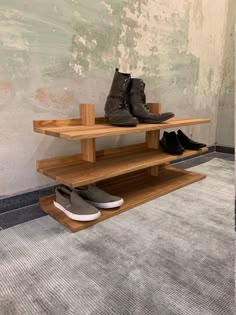 two wooden shelves with shoes on them in front of a wall and carpeted floor