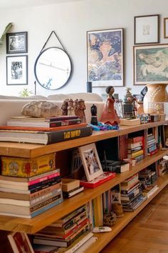 a living room filled with lots of books on top of a wooden shelf next to a couch