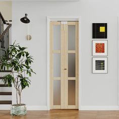 an empty room with stairs and pictures on the wall next to a potted plant