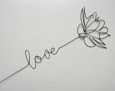 the word love written in metal wire with a flower on it's end and an arrow