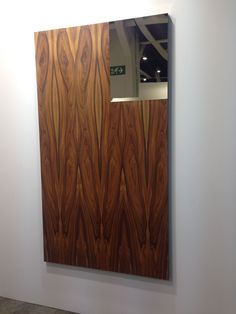 a large mirror mounted to the side of a white wall next to a wooden panel