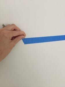 a person is holding a piece of blue tape in their left hand and pointing it at the wall