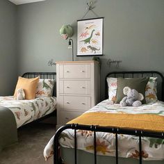 two beds in a bedroom with green walls and white dressers next to each other