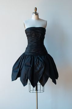 "1980s black petal skirt dress by Victor Costa. 52% nylon 48% polyester. Boning at bodice. Tulle lining at skirt for structure. Plastic zipper, hook & eye and snaps at back.  - Size Extra Small - Bust: 32\" - 34\"  Waist: 25\" Drop Waist: 36\" Bodice: 16\" Hips: Full  Length: 33\" Condition: Excellent!" Waist Drop Dress, 1980 Dresses, 80s Gothic Prom Dress, Drama Gcse, Black Voluminous Full Skirt Petticoat, Gothic Ruffled Corset Dress, Victor Costa Dress, Plastic Skirt, School Disco