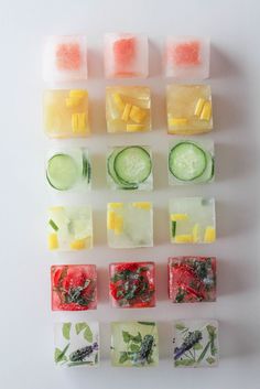 there are many different types of ice cubes on the white surface, including cucumbers and lemon slices