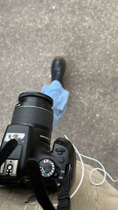 a camera with a lens attached to it sitting on the ground next to a shoe