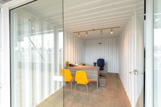 an office with glass walls and yellow chairs