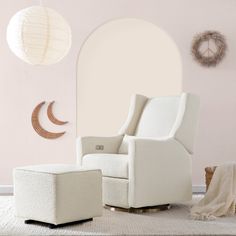 a white chair and ottoman in a living room with a moon decoration on the wall