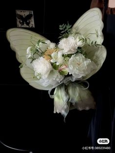 a bouquet of flowers sitting on top of a table next to a black wall with an image of a butterfly