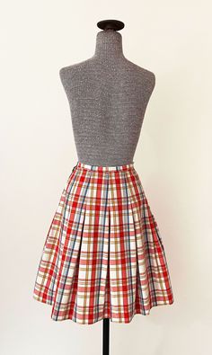 "1960s Miss Pat pleated skirt. Light red, blue, gold and white plaid pattern. High waisted with dropped pleats and a wide A line cut. Side zipper and button closure. In great vintage condition with a couple tiny specks - please see photos. All measurements are taken with the garment laying flat and doubled for the bust, waist, and hips. Waist: 22\" Hips: open Length: 22\" Label: Miss Pat Material: Not listed; looks / feels like cotton or cotton blend Size on Tag: N/A Approx. Fit: XXS Some garmen Classic Pleated Plaid Skirt, Retro Fitted Cotton Pleated Skirt, Fitted Pleated Skirt In 1950s Style, Plaid Flared Pleated Lined Skirt, Fitted Pleated Skirt In Vintage Style, 1950s Style Fitted Pleated Skirt, Plaid Flared Pleated Skirt With Lining, Preppy Plaid Pleated Lined Skirt, Retro A-line Pleated Skirt