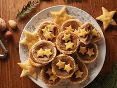 star shaped pastries on a white plate with pine cones and nuts around them, surrounded by christmas decorations