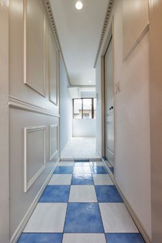 an empty hallway with blue and white tiles on the floor