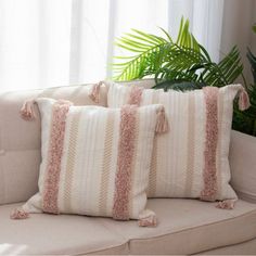 two pillows sitting on top of a couch next to a potted plant