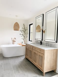 a large bathroom with two sinks and a bathtub in the middle, along with mirrors on the wall