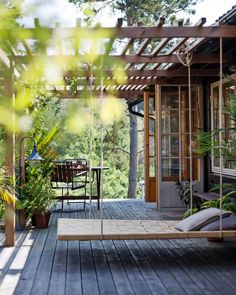 a wooden porch with a swing chair and potted plants on the back deck area