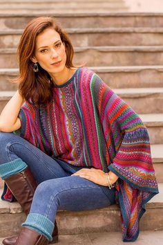 a woman is sitting on the steps with her legs crossed wearing boots and a colorful sweater