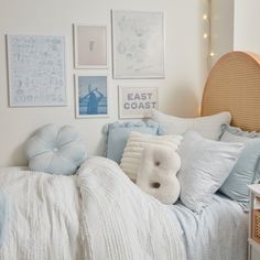 a bedroom with white walls and blue bedding, pillows and pictures on the wall