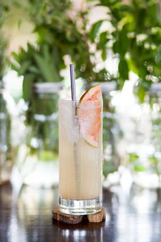 a tall glass filled with ice and a slice of grapefruit sitting on top of a table