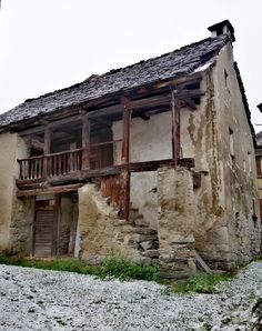 an old run down stone building with wooden balconies on the roof and windows