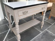 an old white table with black top and drawers