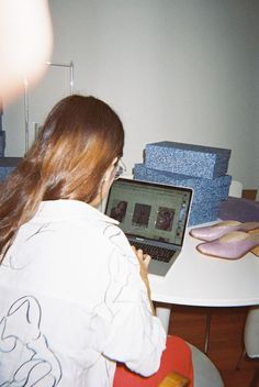 a woman sitting at a table using a laptop computer