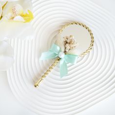 a white flower with a blue ribbon around it and a gold hair comb on a white plate