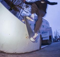 a man riding a skateboard up the side of a cement wall next to a building