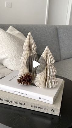 two folded christmas trees sitting on top of a book next to a pillow and pillows