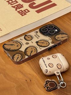 an apple phone case sitting on top of a wooden table next to a pair of keys