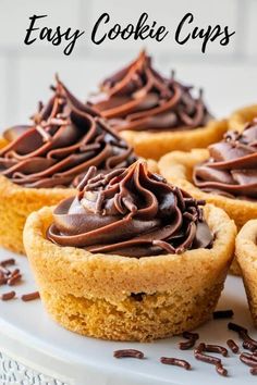 chocolate frosted cupcakes sitting on top of a white cake plate