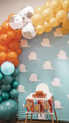 an assortment of balloons and decorations are displayed in front of a wall with clouds on it