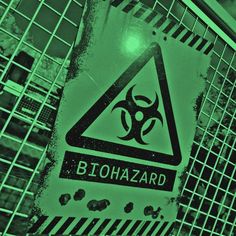 a biohazard sign on a fence in front of an industrial area that is green