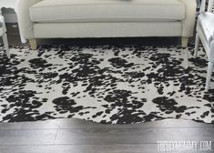 a living room with a white couch and black and white cow print rug on the floor